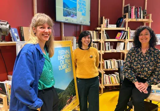 Trois femmes debout devant une affiche du festival