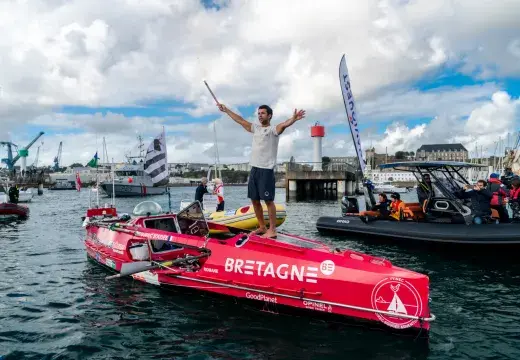 Un hommes les bras levé sur son aviron de mer arrivant au port de Brest devant une foule sur le quai