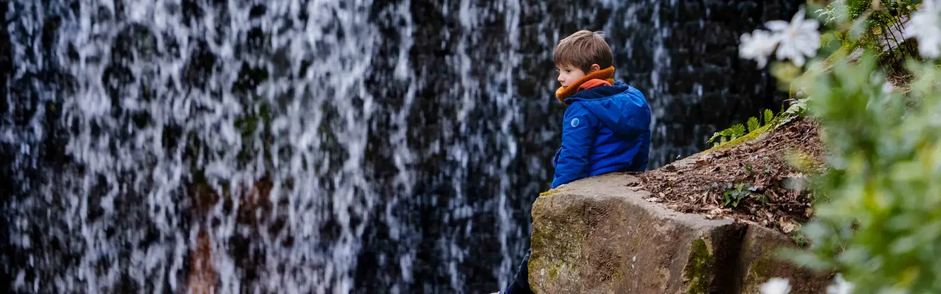 un enfant devant une chute d'eau