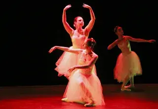 Photo montrant quatre danseuses classiques effectuant des pas sur une scène de spectacle