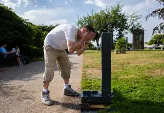 Une personne boit de l'eau à un robinet public
