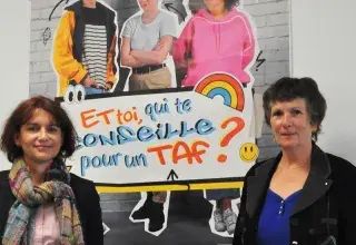 Deux femmes posent autour d'une affiche de la Mission locale du Pays de Brest. 