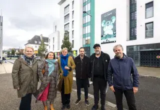 Plusieurs personnes devant un immeuble.