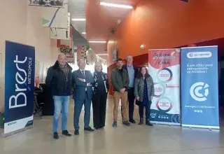 Plusieurs personnes posent devant des affiches.