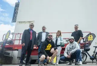 Plusieurs personnes posent devant un mur. 