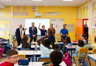Cinq personnes debout devant le tableau du salle de classe.