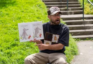 Un homme lit un livre au pied d'une tour.