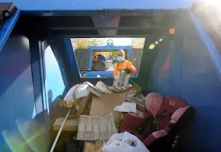 Un homme jette quelque chose dans une benne.