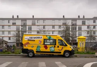 Un camion de tri garé devant des immeubles.