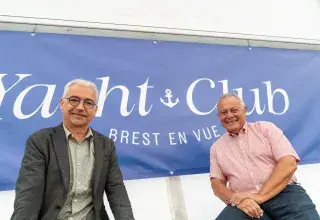 Deux personnes devant une bannière.