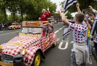 Des spectateurs applaudissent une voiture qui passe. 