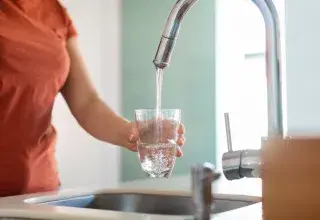 Une femme se sert un verre d'eau au robinet