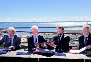Des hommes signent un document officiel sur le parvis de la gare de Brest, au-dessus du port