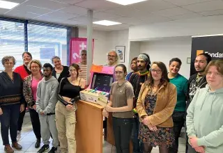 Des femmes et des hommes posent devant une borne d'arcade