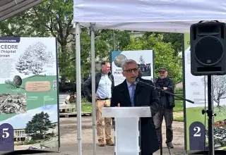 Un homme au micro, devant une exposition en plein air 