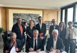 3 hommes derrière un bureau signent un partenariat.