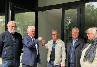 deux hommes échangent des clés devant le local associatif de Quéliverzan