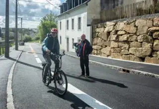 Un cycliste et un piéton se croisent sur une route. 