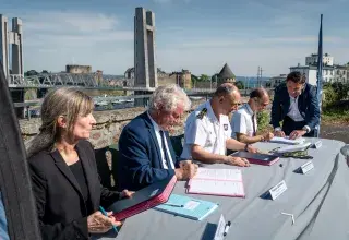 Des hommes et des femmes signent des parapheurs à proximité de la Penfeld
