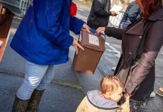 Deux personnes échangent un seau de déchets.