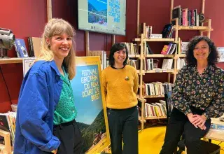 Trois femmes debout devant une affiche du festival