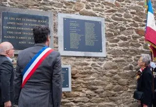 Trois personnes se tiennent devant des plaques commémoratives.