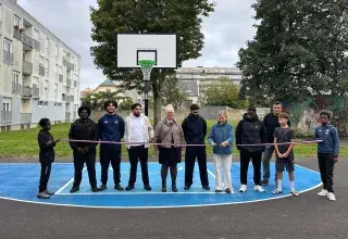 Des personnes coupant un ruban devant un terrain de basket.