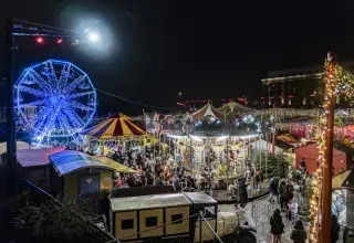 Photo montrant un village de Noël illuminé à la nuit tombée 