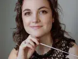 Photo montrant une jeune femme posant avec une baguette de cheffe d'orchestre